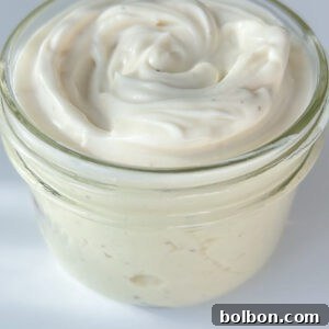 A small glass jar filled with creamy white Egg Free Mayo, its smooth, swirled surface invitingly displayed against a white background.