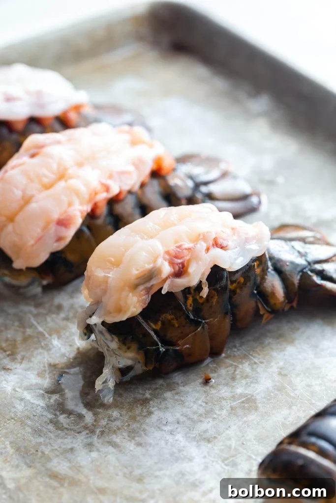 Close-up of butterflied lobster tails arranged on a baking sheet before broiling