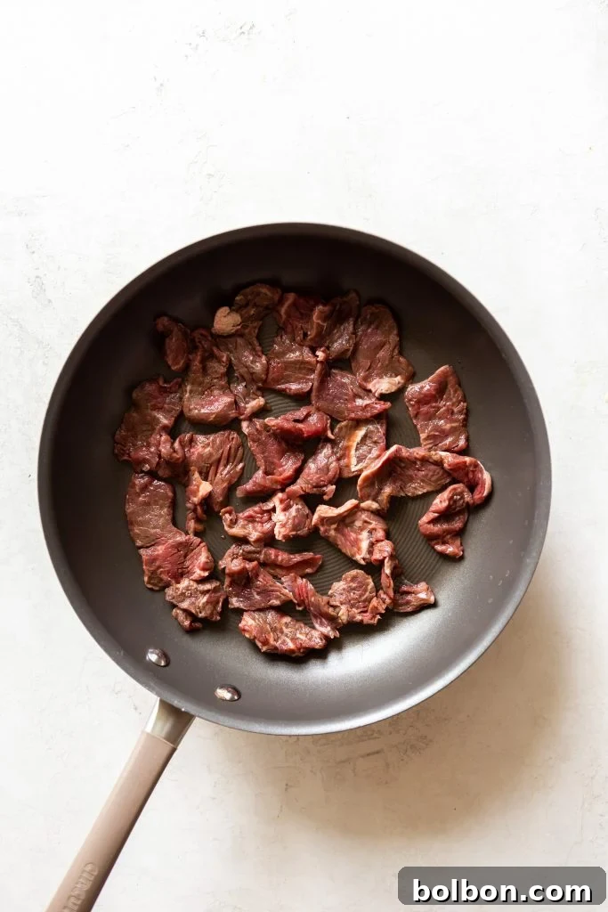 Thinly sliced beef being prepared for Beef Stroganoff.