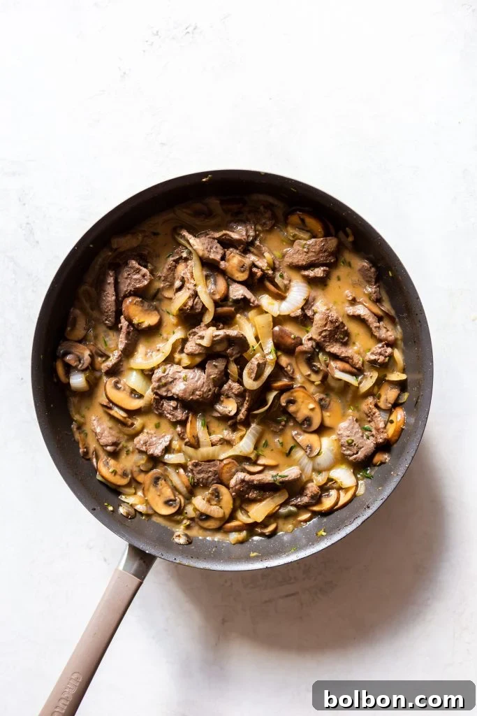 A pan with mushrooms cooking, releasing their liquid.