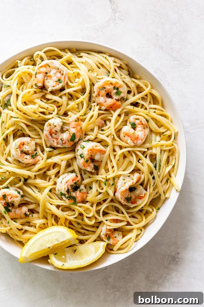 A serving of Shrimp Scampi Pasta in a pristine white bowl, garnished with fresh parsley and a lemon wedge, ready to be enjoyed.