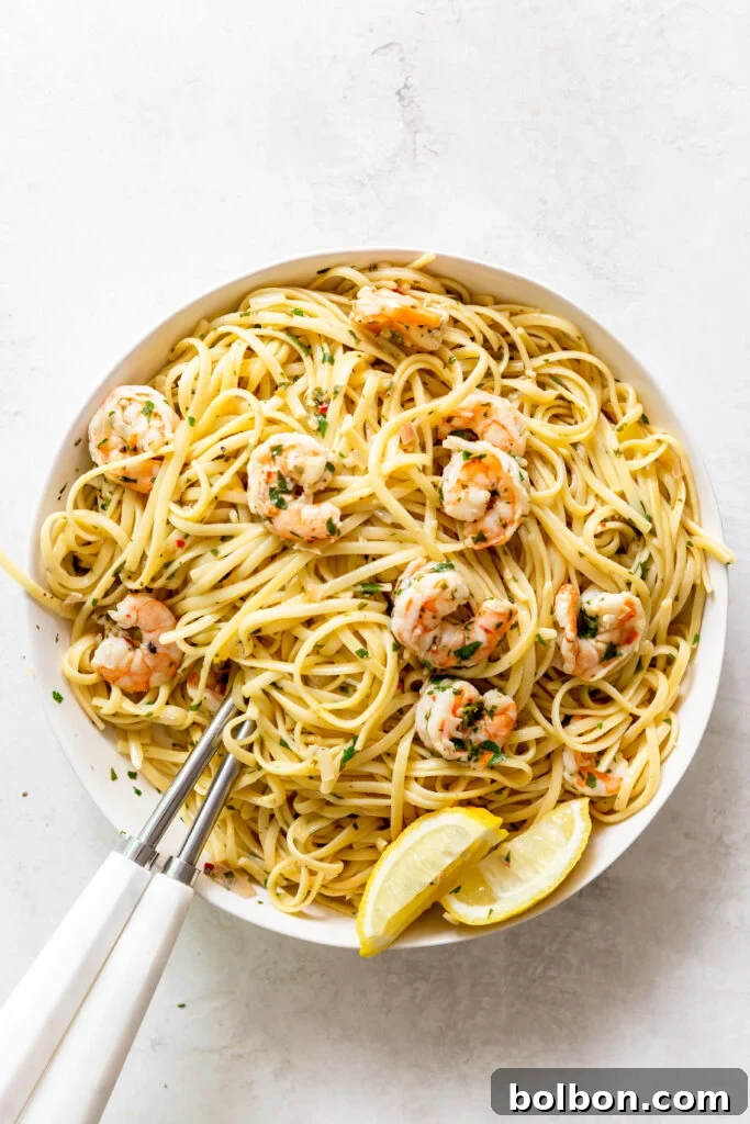 Shrimp Scampi Pasta elegantly presented in a white bowl, with white serving utensils resting alongside, highlighting its appealing texture.