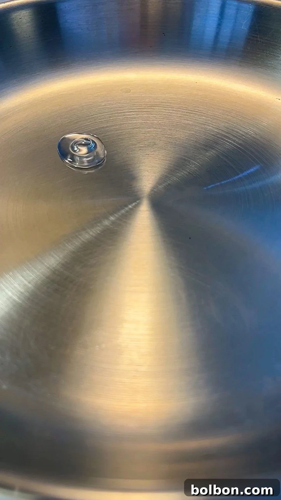 Properly preheated stainless steel pan with a single drop of water demonstrating the Leidenfrost effect, showing how to make stainless steel non stick