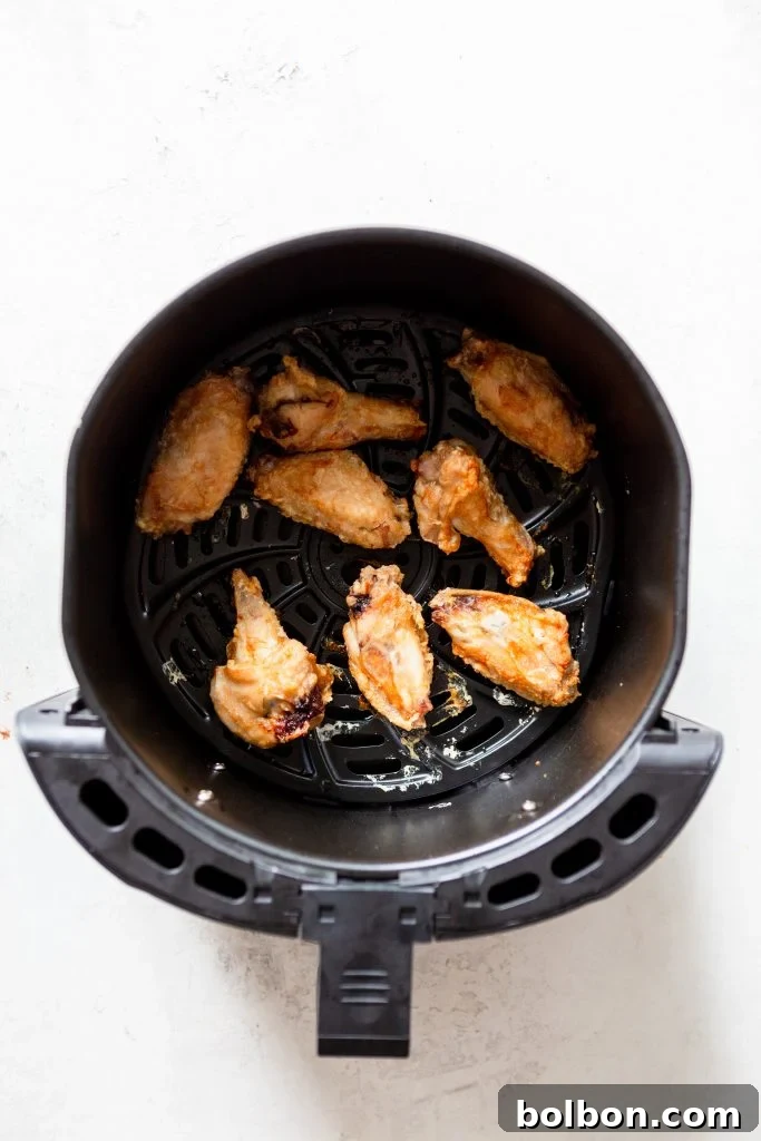 Chicken wings cooking in an air fryer basket