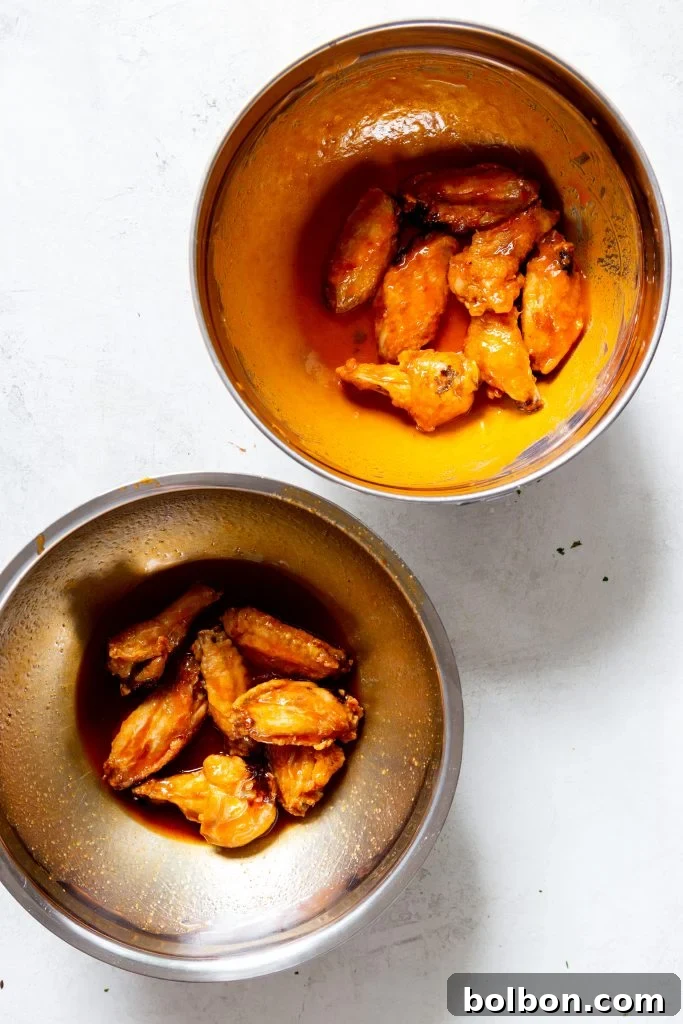 Air-fried buffalo wings being sauced in a bowl