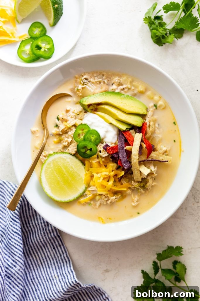 One-Pot Cozy White Chicken Chili 2 Creamy white chicken chili in a white bowl, topped with avocado slices, sour cream, shredded cheese, tortilla strips, jalapeno slices and a lime wedge.