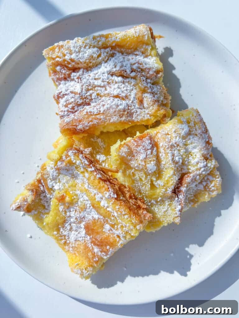 Overnight French Toast Bake 2 A golden-brown French Toast Casserole, dusted with powdered sugar and garnished with fresh berries, on a rustic wooden surface, ready to be served for a delightful breakfast or brunch.