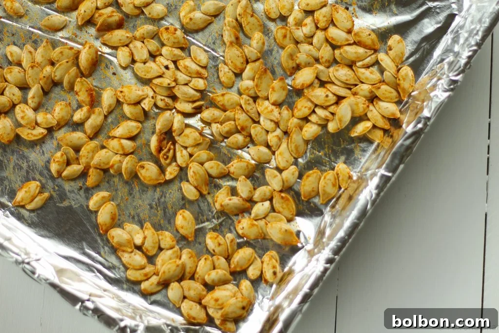Pumpkin seeds tossed with olive oil and curry powder in a bowl, before going into the oven.