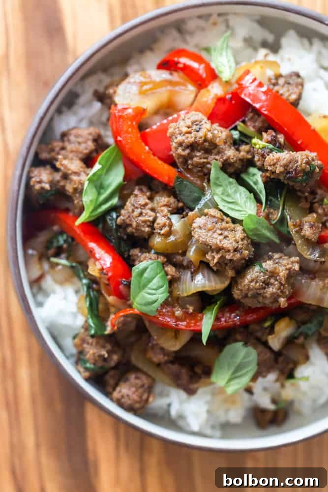 Spicy Thai Basil Beef 2 Thai basil beef with fresh basil, red bell peppers and onions over white rice, garnished with more fresh basil leaves.