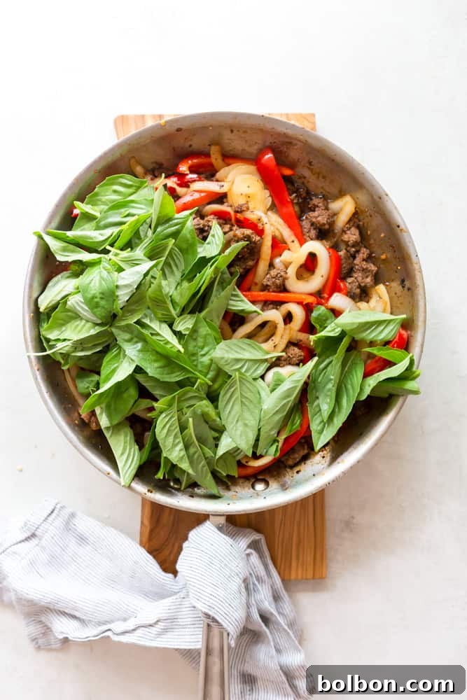 Spicy Thai Basil Beef 7 Sauce being poured over the beef and vegetables in the skillet for Thai basil beef.