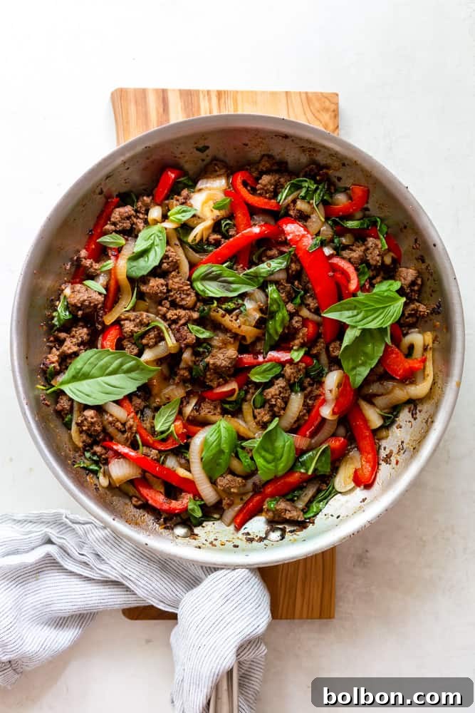 Spicy Thai Basil Beef 8 Thai basil beef in a large stainless steel skillet, garnished with fresh basil, ready to be served.