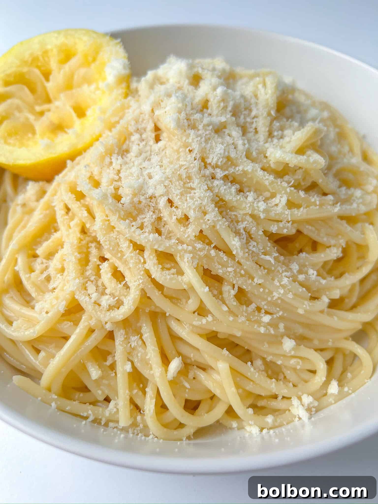 Zesty Lemon Pasta 2 A vibrant bowl of Pasta Limone, featuring spaghetti coated in a rich, creamy lemon sauce, garnished with fresh herbs and a generous sprinkle of grated Parmesan cheese.