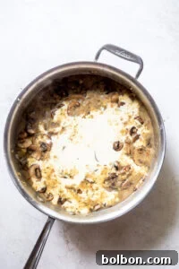 Heavy cream added to the mushroom sauce, which is thickening.