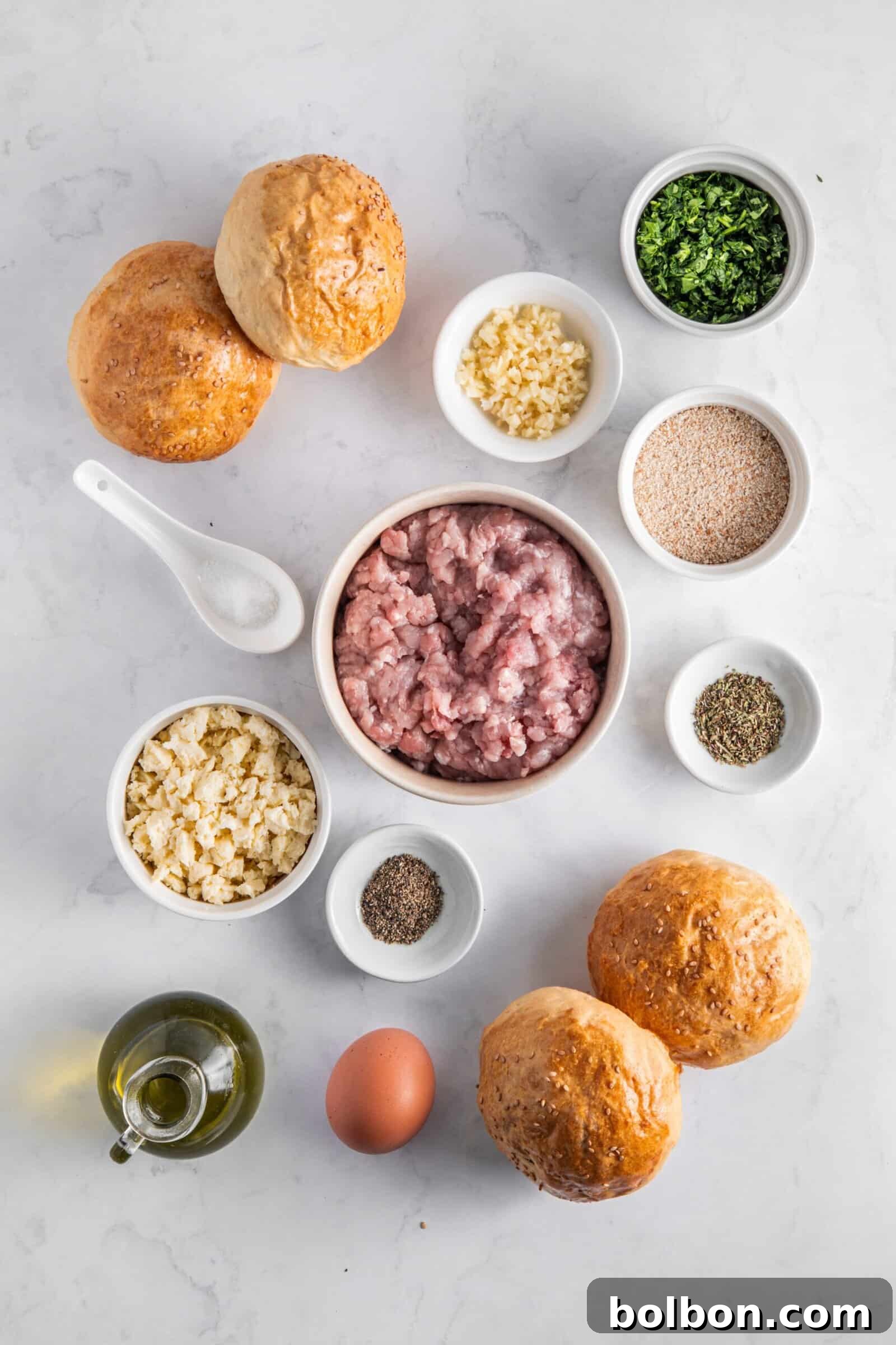 Next-Level Turkey Burgers 3 Fresh ingredients for turkey burgers including ground meat, chopped garlic, fresh dill, breadcrumbs, spices, and an egg, all neatly arranged on a marble counter.