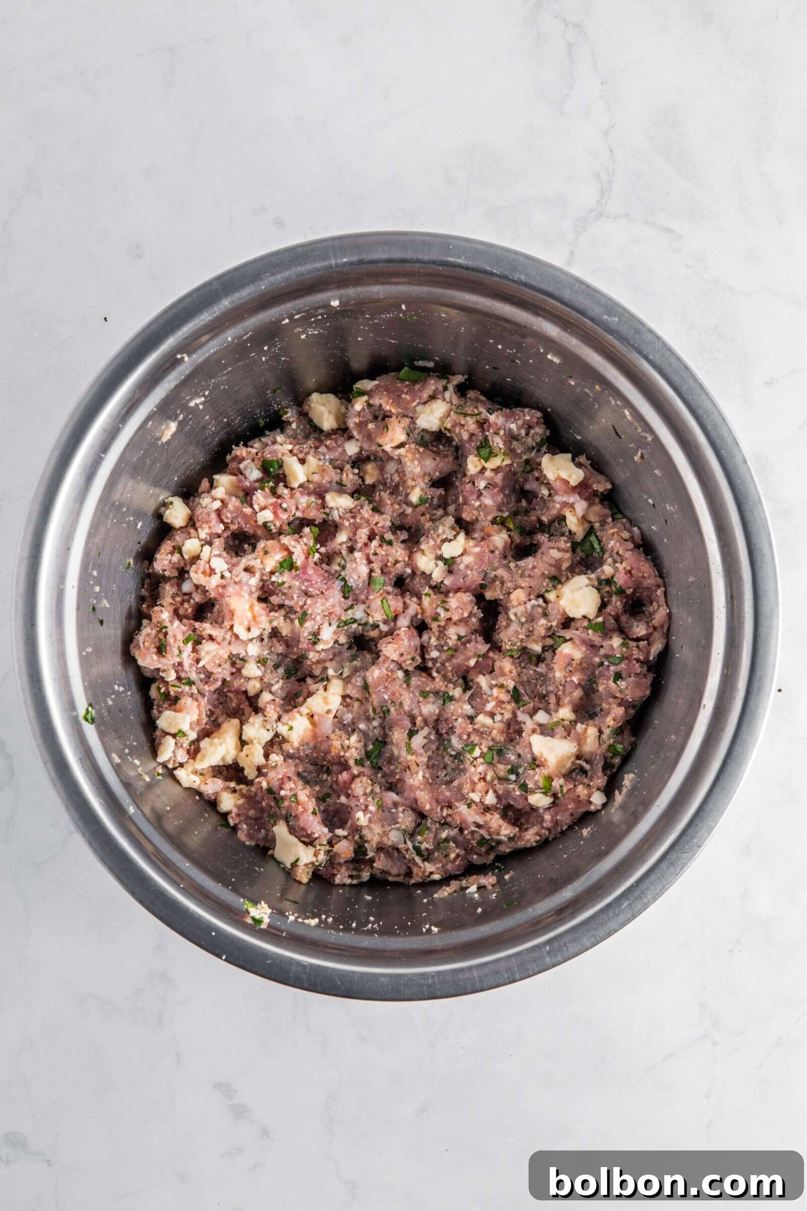 Next-Level Turkey Burgers 6 The well-chilled and seasoned ground meat mixture in a metal bowl, exhibiting a firm texture after refrigeration, awaiting shaping into burger patties.