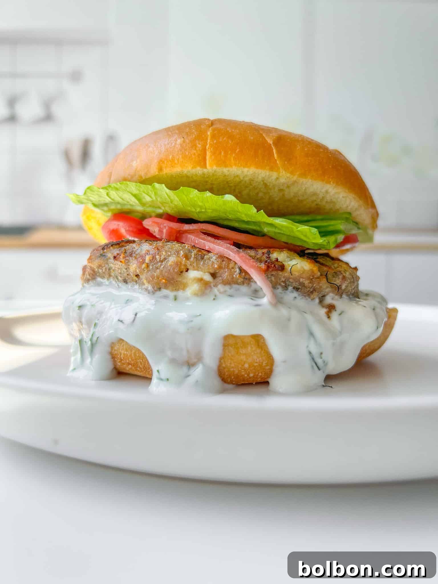 Next-Level Turkey Burgers 10 A magnificent Greek-inspired turkey burger, fully assembled with creamy tzatziki, crisp lettuce, and pickled onions, ready to be enjoyed.