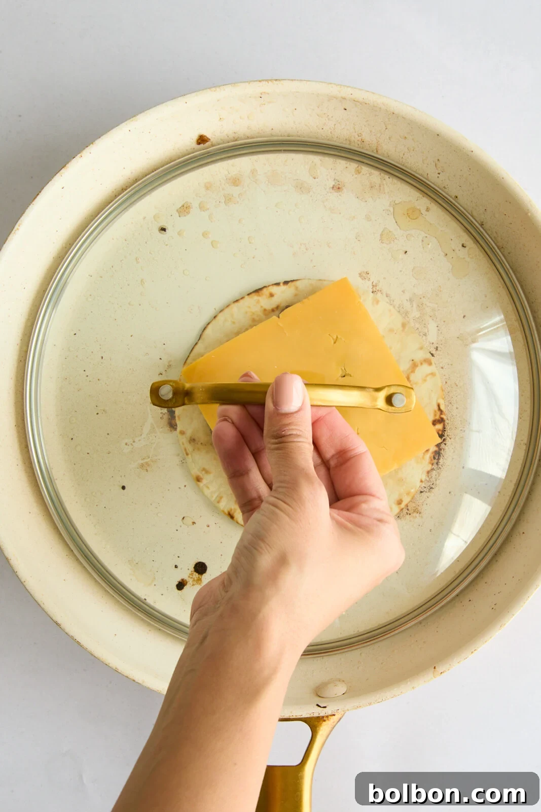 A Big Mac Smash Taco in the pan with a lid, allowing the cheese to perfectly melt over the beef patty, signifying the final cooking step.