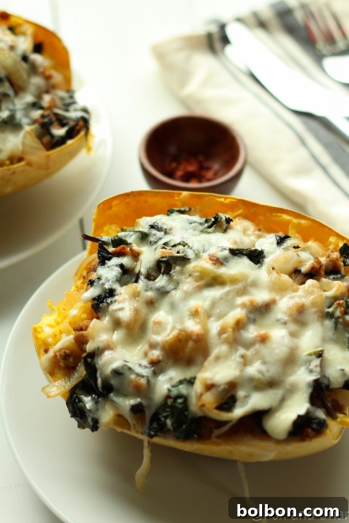 Close-up of a bubbling Sausage and Kale Spaghetti Squash Boat with vibrant green kale.