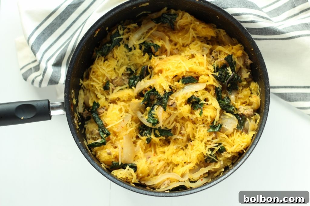 Kale and sausage mixture cooking in a large pan on the stovetop.