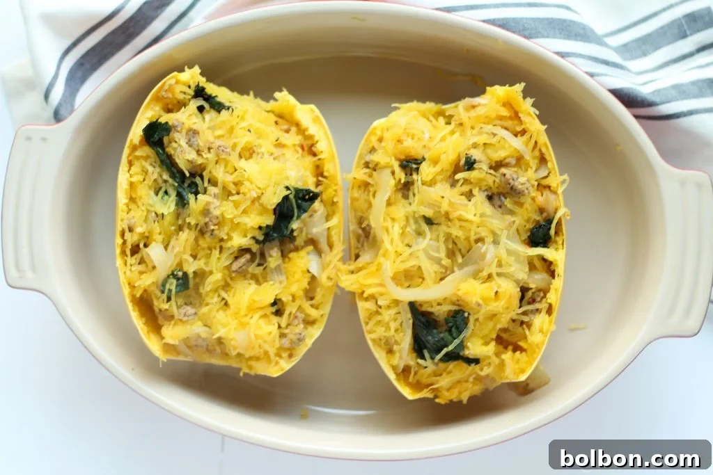 Filled spaghetti squash boat topped with mozzarella cheese, ready for baking.
