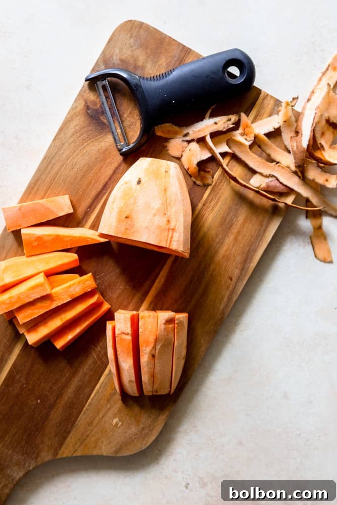 A sweet potato cut in half lengthwise on a cutting board.