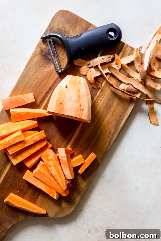 A pile of evenly cut raw sweet potato fries ready for seasoning.
