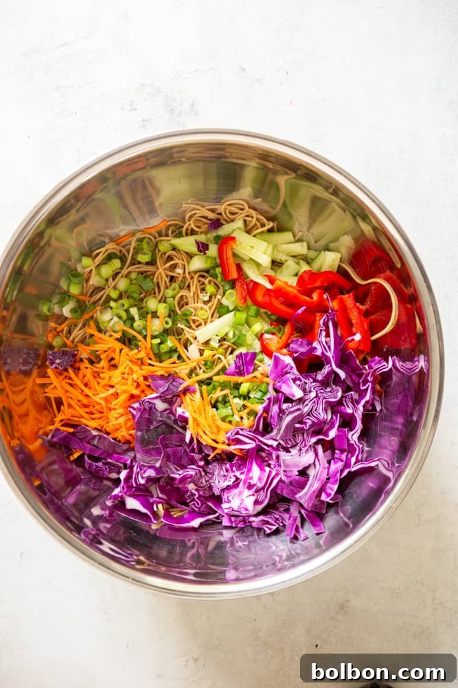 Zesty Peanut Noodles 5 Chopped purple cabbage, grated carrots, sliced green onion, sliced cucumber and sliced re bell pepper in a large bowl with cooked spaghetti