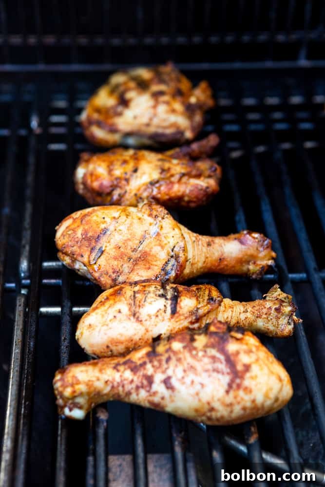 Golden-brown chicken drumsticks and thighs sizzling on a hot grill, marked with perfect char lines that signify delicious flavor development. The image captures the dynamic energy of grilling, with subtle smoke adding to the ambiance.