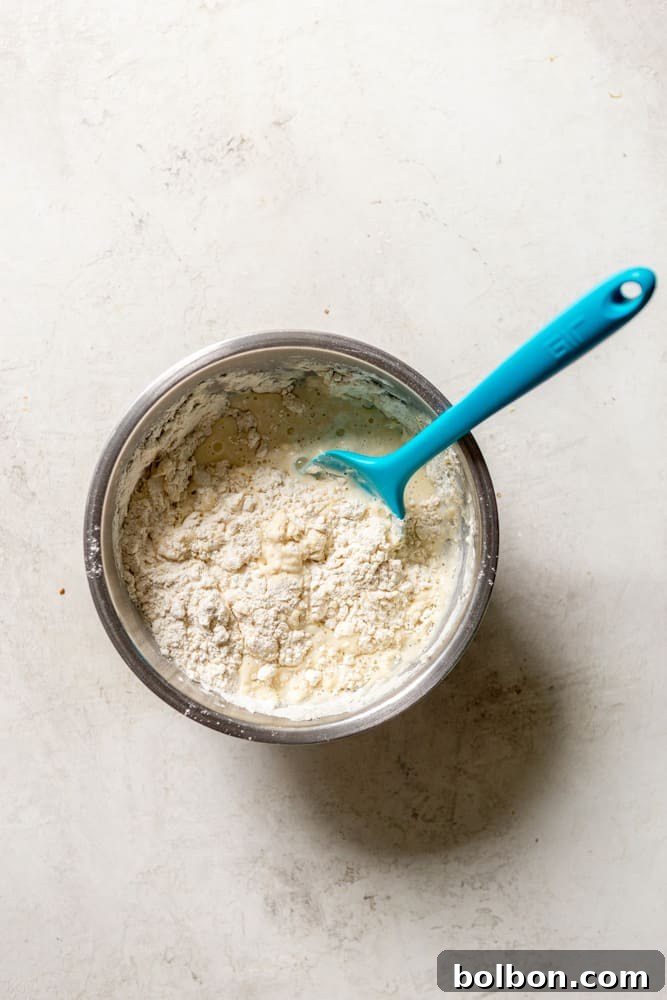A close-up view of dumpling dough being gently mixed, showing the careful technique to avoid overworking the flour and ensuring light, fluffy dumplings.