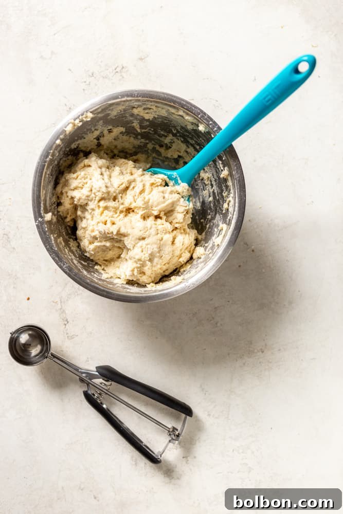 A close-up shot of fluffy dumpling dough, perfectly scooped with a medium cookie scoop, ready to be dropped into the simmering stew.
