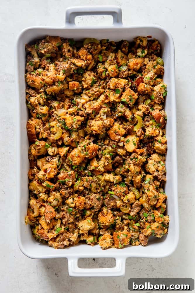 Timeless Savory Sausage Stuffing 10 A delicious classic sausage stuffing, golden brown and crispy, in a white baking dish on a wooden board with serving spoon.