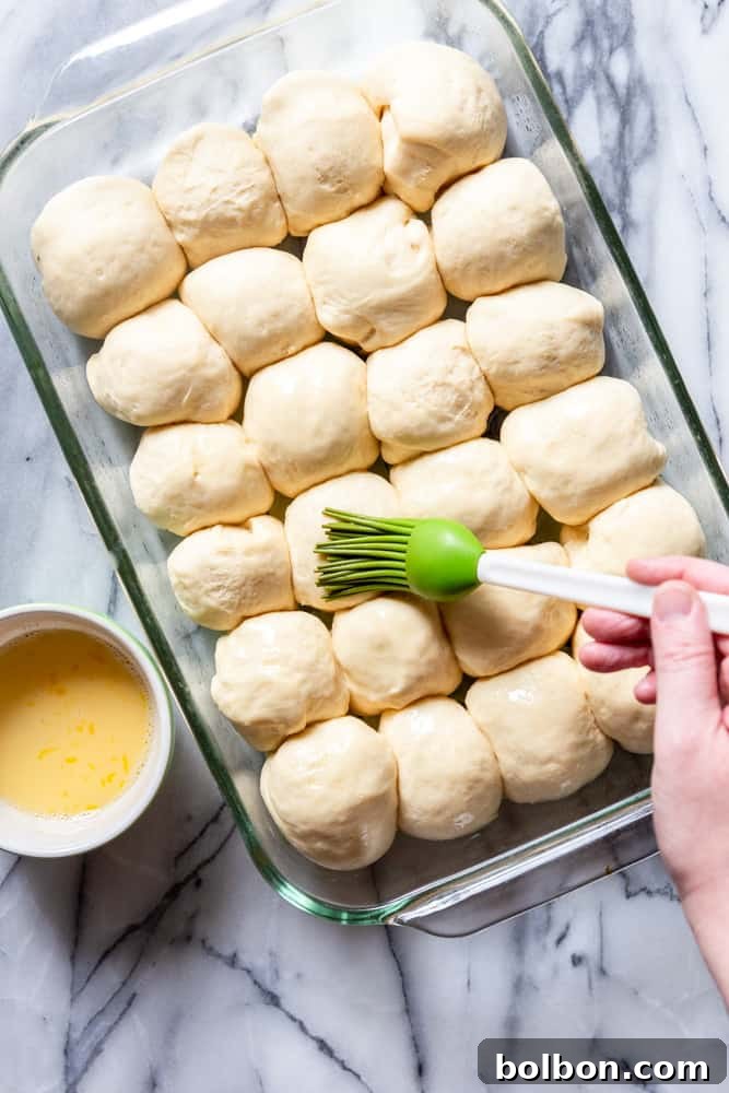 Effortless Dinner Rolls 8 Dough balls being brushed with egg wash before baking