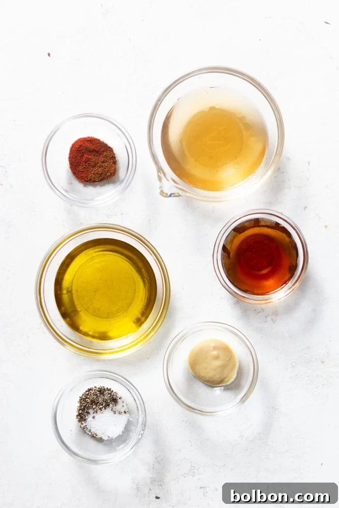 Ingredients for apple cider vinaigrette - apple cider vinegar, olive oil, maple syrup, Dijon mustard, salt and pepper, smoked paprika and chili powder.