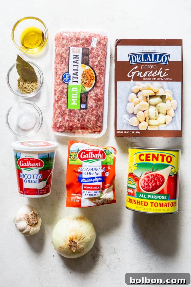 Hearty One-Pan Gnocchi & Sausage 3 Arrangement of fresh ingredients for one-pot gnocchi, including ground Italian sausage, shelf-stable potato gnocchi, creamy ricotta cheese, whole milk low-moisture mozzarella, a can of crushed tomatoes, fresh garlic cloves, a yellow onion, salt, dried oregano, a bay leaf, and olive oil.