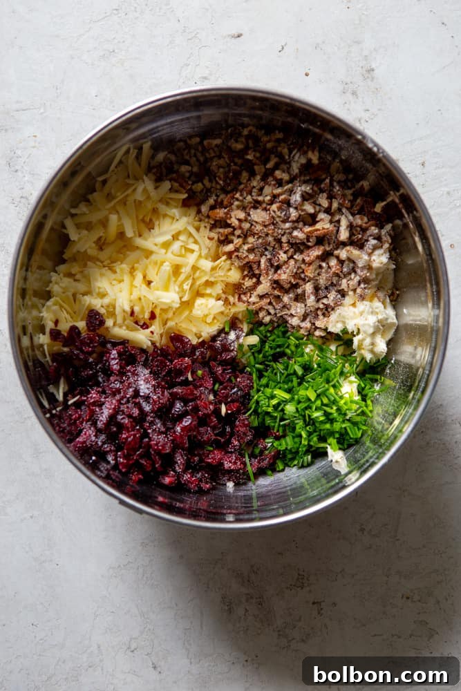 Finely chopped dried cranberries, toasted pecans, fresh chives, and shredded sharp white cheddar cheese, all ready to be mixed into the creamy base for the cheese ball.