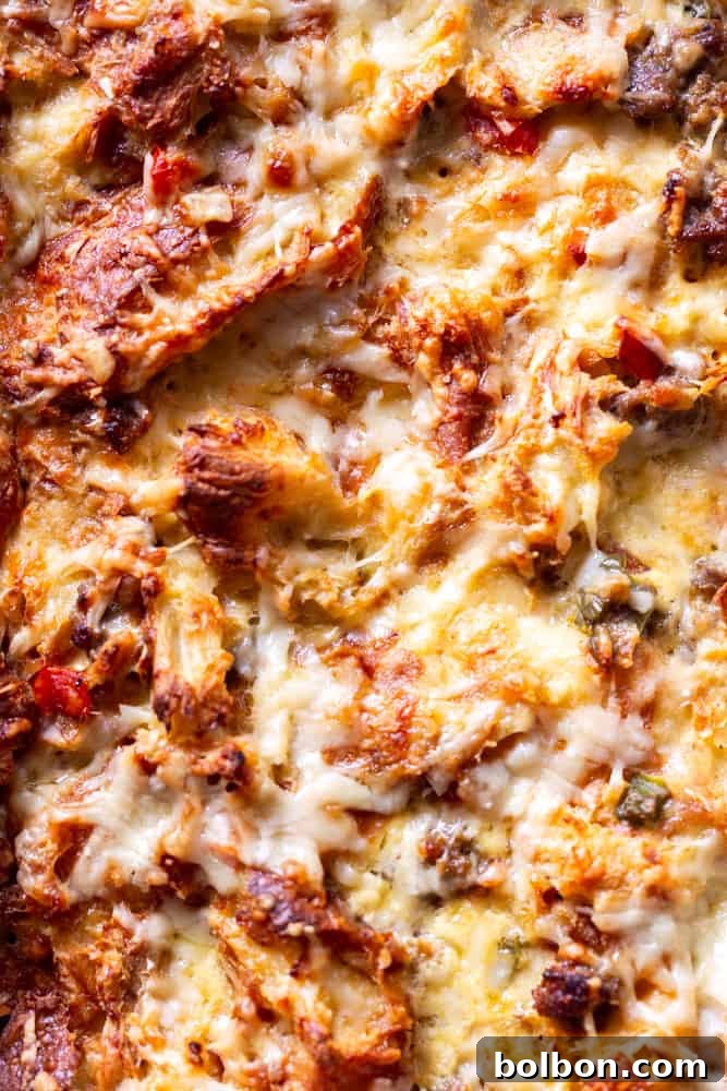 A close-up shot of the baked make-ahead breakfast casserole, revealing its golden-brown crust and bubbly, savory interior.