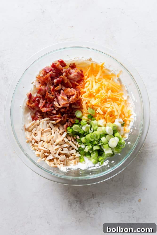 Irresistible Party Dip 5 glass bowl with cream cheese mix topped with bacon, shredded cheese, green onions and slivered almonds.
