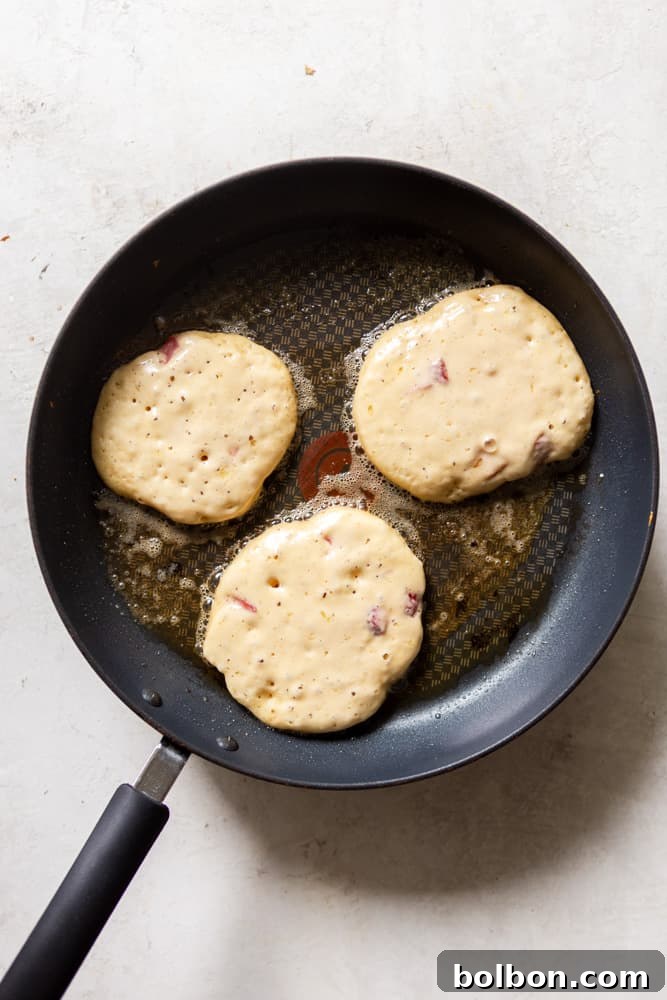 strawberry pancakes before flipping in a non stick frying pan