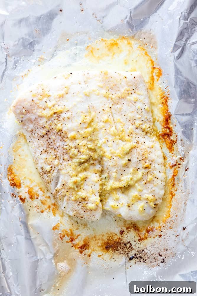 Halibut filet with Garlic Butter after being baked on a foil lined baking sheet.