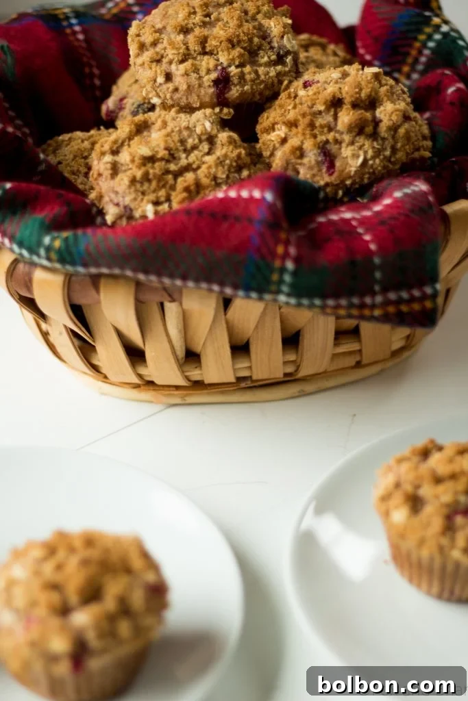 A stack of three cranberry orange muffins, showing their fluffy texture and the delicious streusel topping.