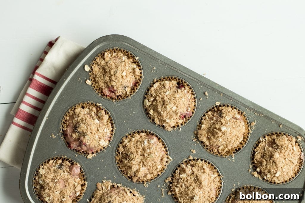 An overhead view of freshly baked cranberry muffins with streusel, arranged artfully on a cooling rack.