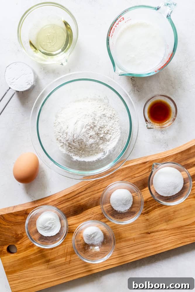 Ingredients for Buttermilk Waffles: Flour, cornstarch, baking powder, baking soda, salt, sugar, vanilla extract, egg, buttermilk, oil, neatly arranged.