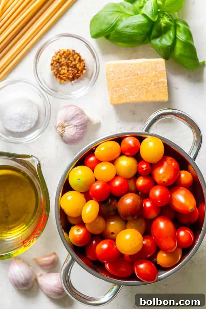 A vibrant selection of ingredients for Burst Cherry Tomato Pasta sauce laid out: colorful cherry tomatoes, whole garlic cloves, a bottle of olive oil, a wedge of Parmesan cheese, a sprinkle of salt and red pepper flakes, fresh basil leaves, and a portion of uncooked pasta.