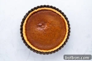 A baked pumpkin pie fresh out of the oven, golden and slightly puffed, cooling on a wire rack.