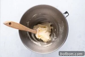 Fluffy whipped cream being prepared in a mixing bowl with a hand mixer.