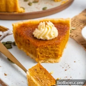 A beautifully baked pumpkin pie, golden brown and ready to be served, sitting on a wooden board.