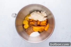 A bowl of rich pumpkin pie filling being whisked, showing the creamy texture and vibrant color.