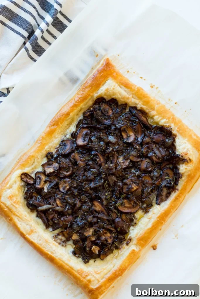 A beautifully presented slice of savory mushroom and gruyere tart, garnished with fresh herbs.