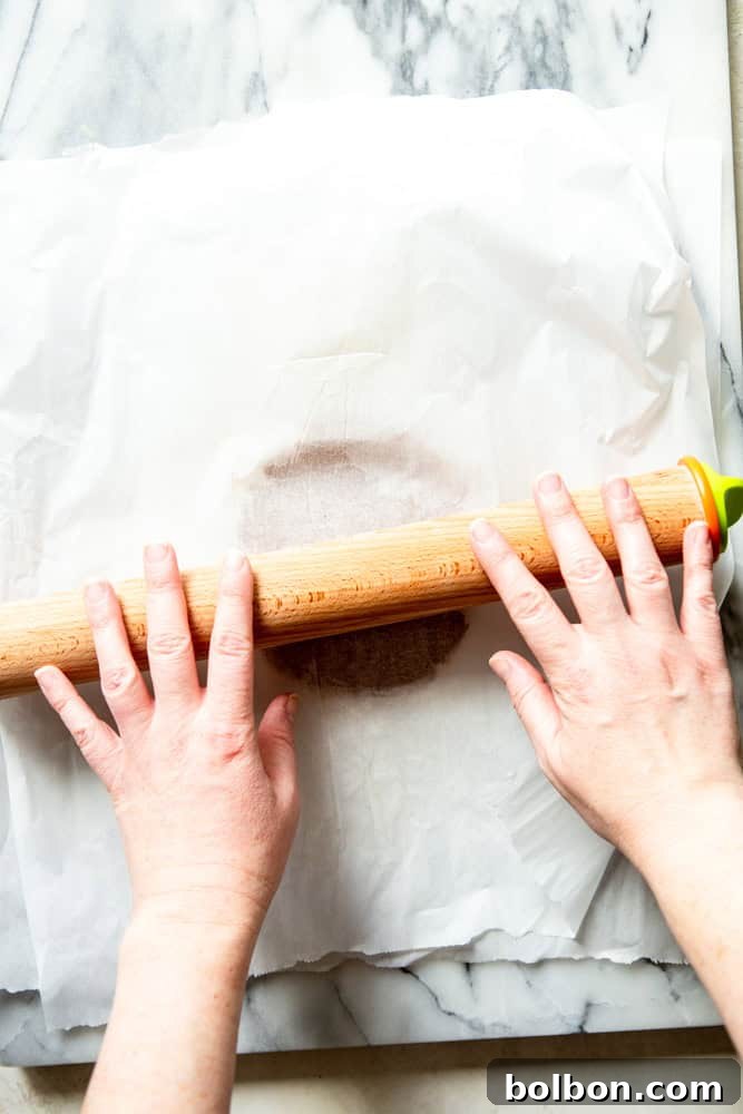 Rolling the gingerbread dough between two sheets of parchment paper.