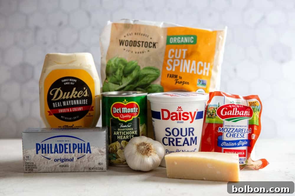A vibrant flat lay of all ingredients for spinach artichoke dip: cream cheese, sour cream, mayonnaise, shredded mozzarella, grated parmesan, fresh spinach, canned artichoke hearts, minced garlic, lemon, and red pepper flakes.